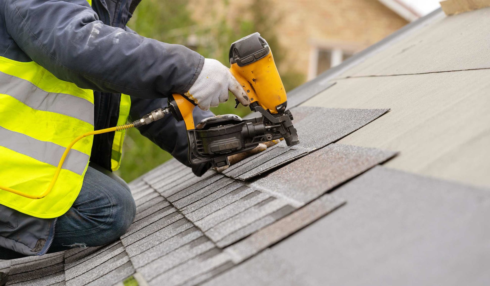contractor hands close up with nailgun installing asphalt shingles at property roof woodstock ga
