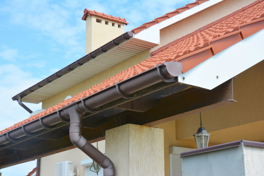 residential gutter of a beige yellowish house with a light brown roofing