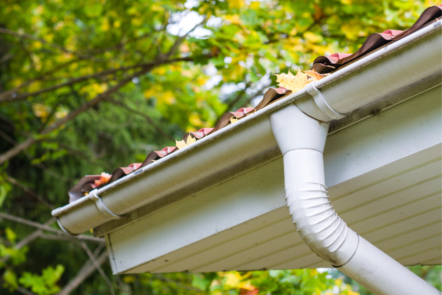 white residential gutter with some leaves on